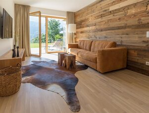 Living room with brown sofa, wood panel wall, and glass doors.
