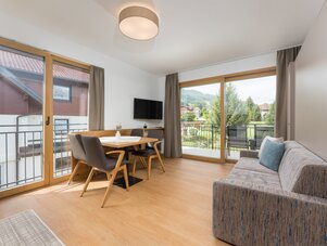 Heller Wohn- und Essbereich mit Holztisch und Glasschiebetüren zum Balkon