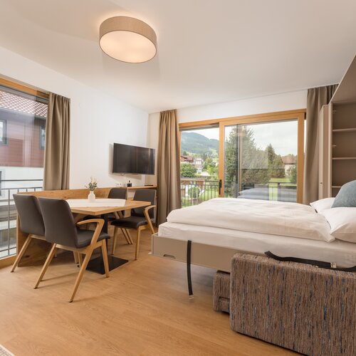 Helles Hotelzimmer mit Esstisch und Balkonblick