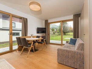 Wohnzimmer mit Esstisch, TV und Glas-Schiebetüren