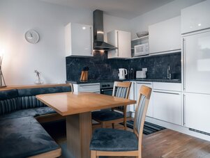 Moderne weiße Küche mit schwarzer Marmor-Rückwand und Essecke