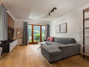 Gemütliches Wohnzimmer mit grauem Ecksofa und Holzboden