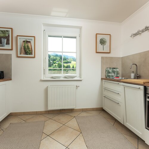 Helle moderne Küche mit weißen Schränken, beigen Fliesen und Fensterblick