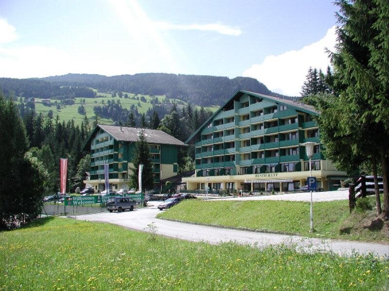 Zwei grüne Alpenhotels mit Restaurant und Willkommensbanner