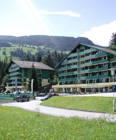 Zwei grüne Alpenhotels mit Restaurant und Willkommensbanner