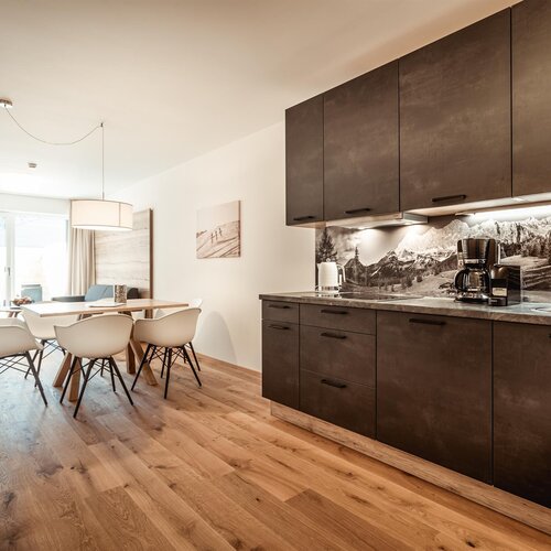 Moderne Küche mit dunklen Schränken, Holzboden und Esstisch.