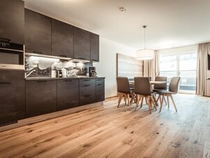 Offene Küche mit dunklen Schränken und Esstisch