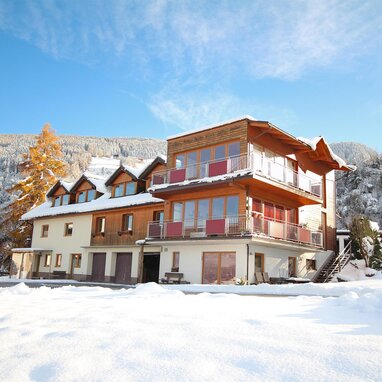 Snowy alpine chalet building with balconies and trees