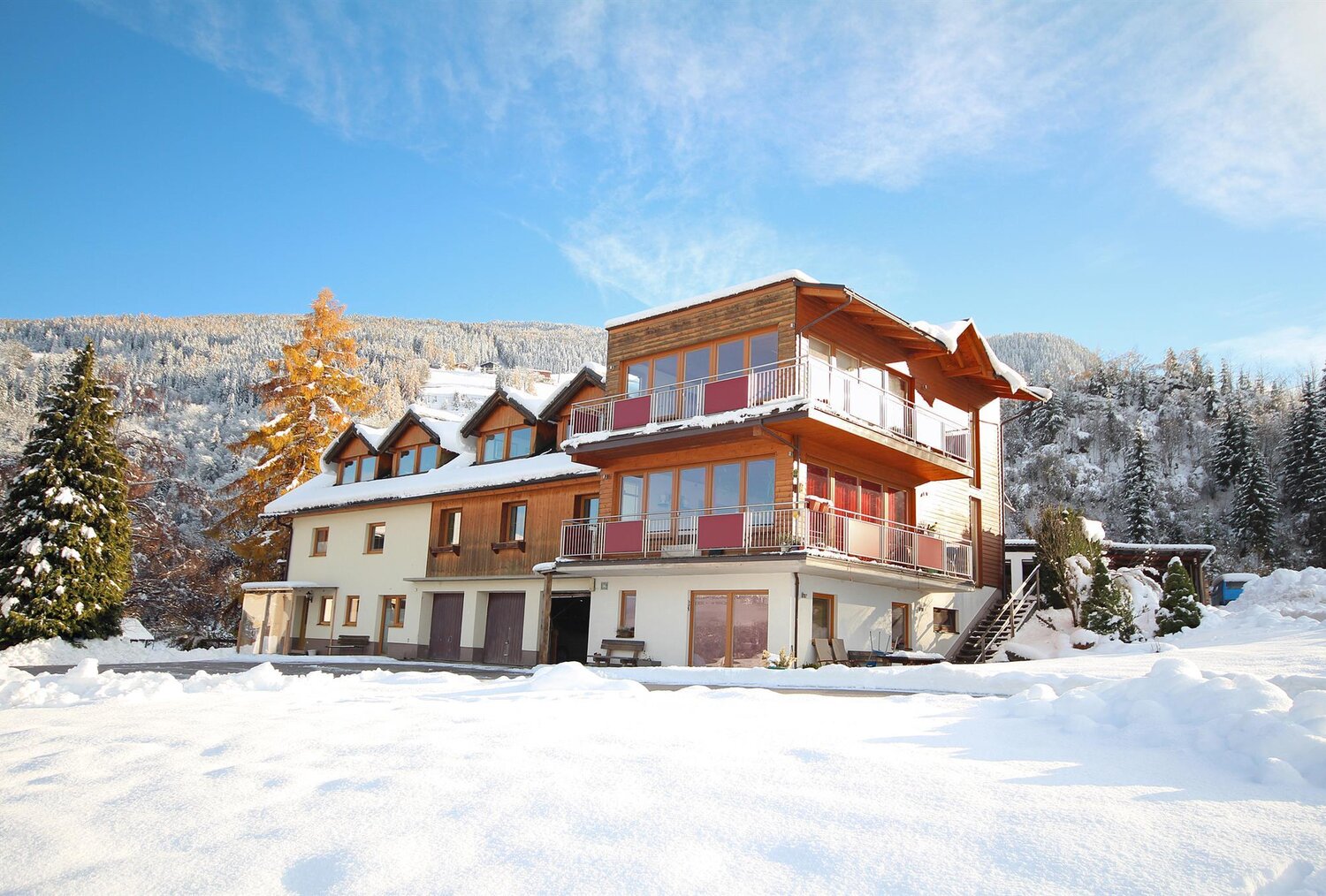 Snowy alpine chalet building with balconies and trees