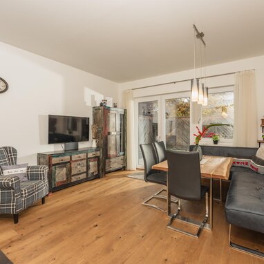 Wohnzimmer mit Esstisch, Sofa, Plaidsessel und rustikalem Sideboard