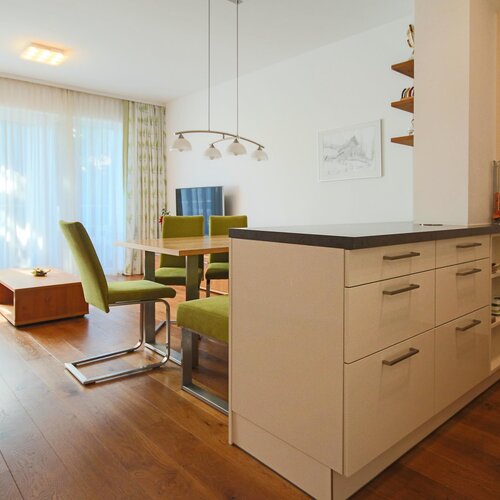 Offener Wohnbereich mit Kücheninsel und grünem Stuhlset