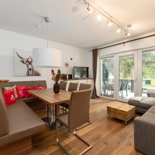 Modernes Wohnzimmer mit Esstisch, Sofa und großen Glastüren