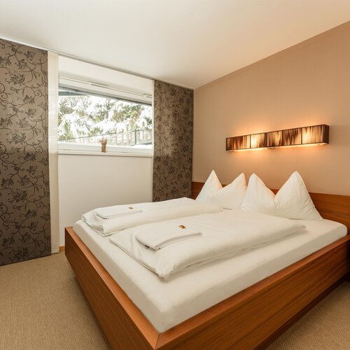Hotel bedroom with wooden bed, pillows, and warm lighting