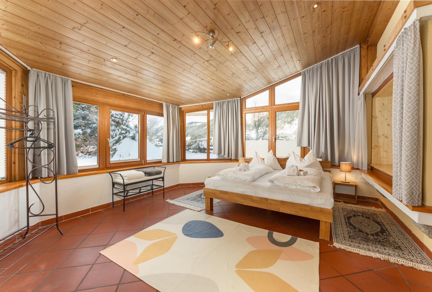 Cozy wooden bedroom with large windows and bed
