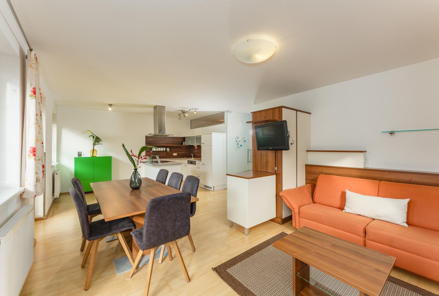 Offener Wohnbereich mit orangefarbener Couch und Esstisch