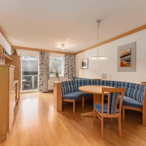 Helles Wohnzimmer mit blau gestreifter Sitzbank und rundem Tisch