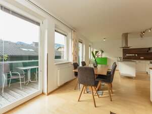 Heller Essbereich mit offener Küche und Balkon