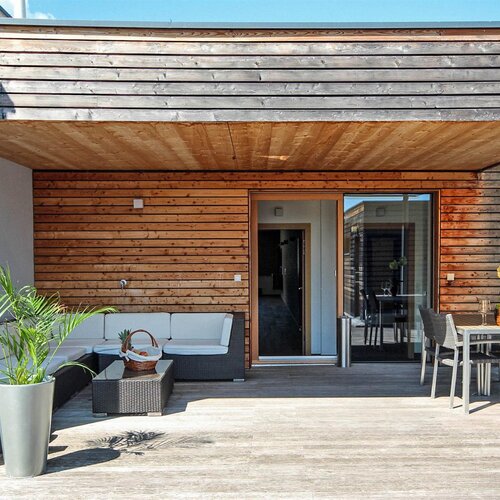 Wood-clad terrace with sofa seating and a dining area
