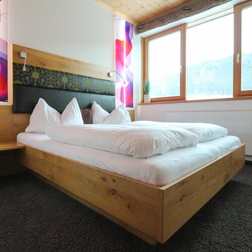 Wooden platform bed with white bedding in bright hotel room | © SCHLADMING-APPARTEMENTS