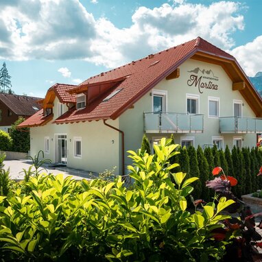 Appartementhaus Martina mit rotem Dach in alpiner Landschaft