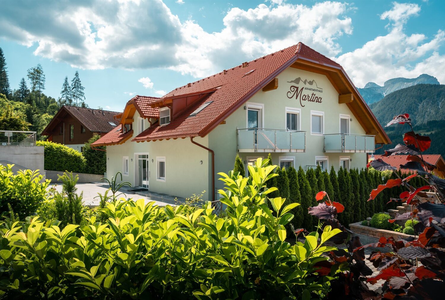 Appartementhaus Martina mit rotem Dach in alpiner Landschaft