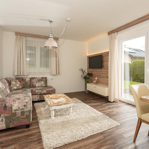 Helles Wohnzimmer mit gemustertem Sofa, Couchtisch und Fernseher