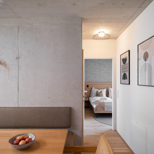 Essbereich neben Betonwand, Blick ins Schlafzimmer