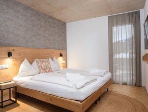 Schlafzimmer mit großem Holzbett und grauer Akzentwand