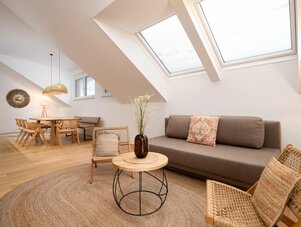 Heller Loft-Wohnbereich mit Dachfenstern, Sofa und Korbmöbel.