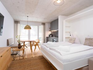 Helles Open-Plan-Studio mit Bett, Esstisch und Küche