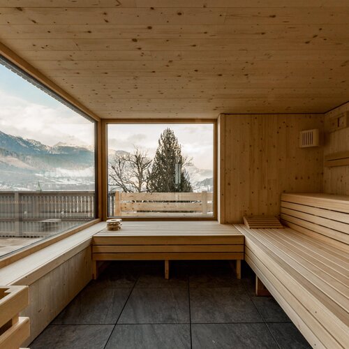 Holzsauna-Innenraum mit großem Fenster und Bergblick