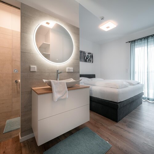 Modernes Hotelzimmer mit offener Dusche und Bett