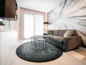 Modern living room with gray sofa, circular coffee tables, and tree mural