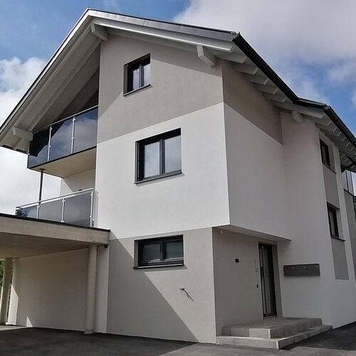 Modernes mehrstöckiges weißes Haus mit Einfahrt und Carport