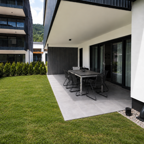 Moderne überdachte Terrasse mit Esstisch und Stühlen.