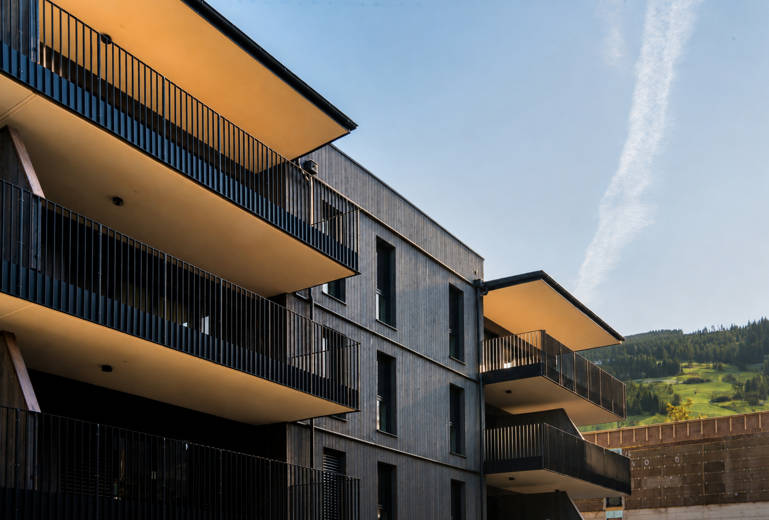 Modernes Wohngebäude mit übereinander gestapelten Balkonen und blauem Himmel