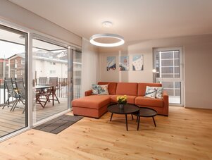 Wohnzimmer mit orange Eckcouch und runden Tischen