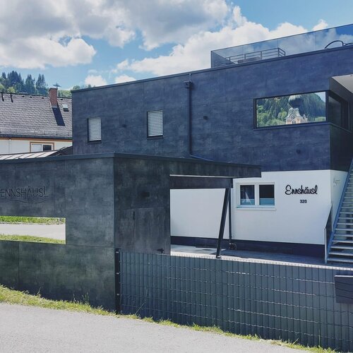 Modern dark two-story house with white wall and sign