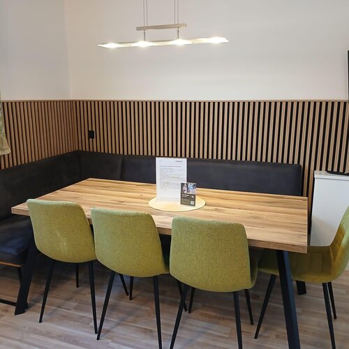 Modern dining area with wooden table, corner bench and green chairs