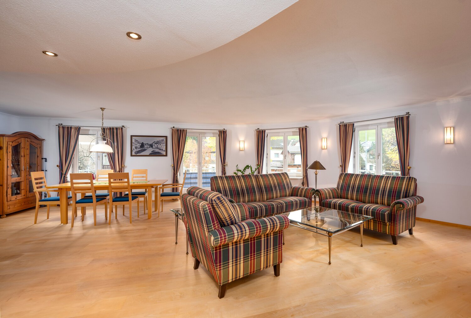 Spacious living and dining room with plaid sofas and wooden furniture