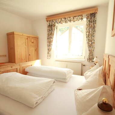 Gemütliches Schlafzimmer aus Holz mit zwei Betten und Kleiderschrank