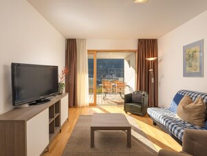 Modern living room with flat-screen TV, sofa, and balcony.