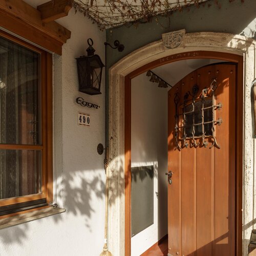 Arched wooden doorway with decorative iron grate and wall sculpture