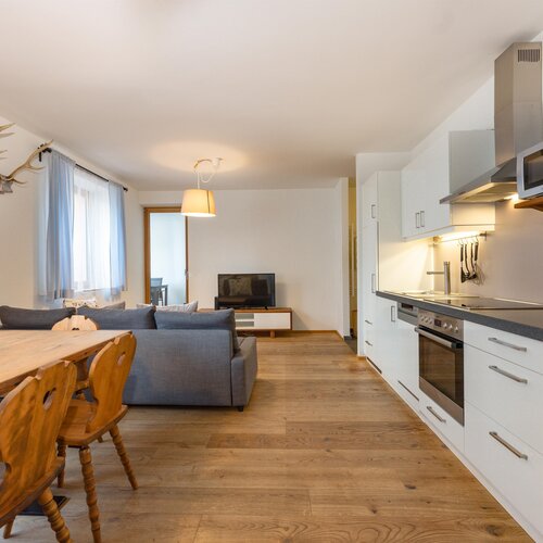 Open plan living area with dining table, sofa, and kitchen.