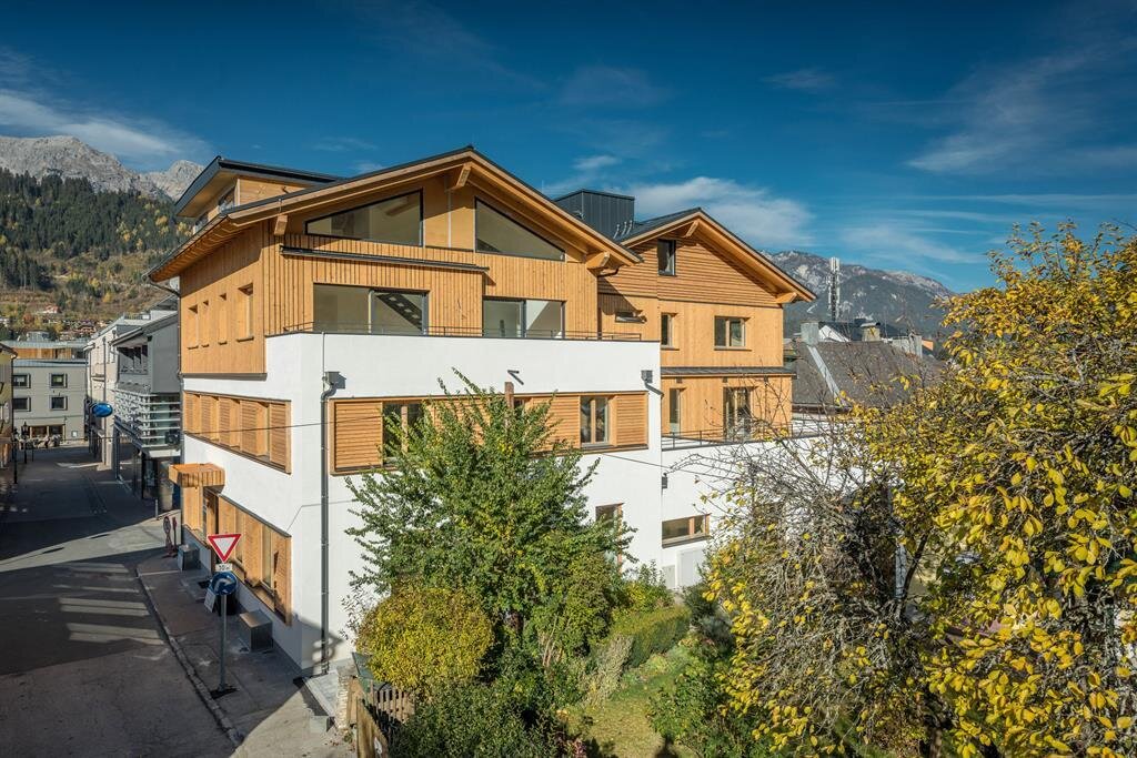 Modern wooden-clad apartment building along street with trees