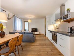 Open-plan living area with dining table, sofa, and kitchen
