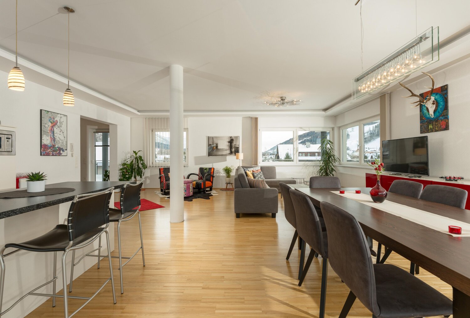 Offener Küchen-, Ess- und Wohnbereich mit großen Fenstern.