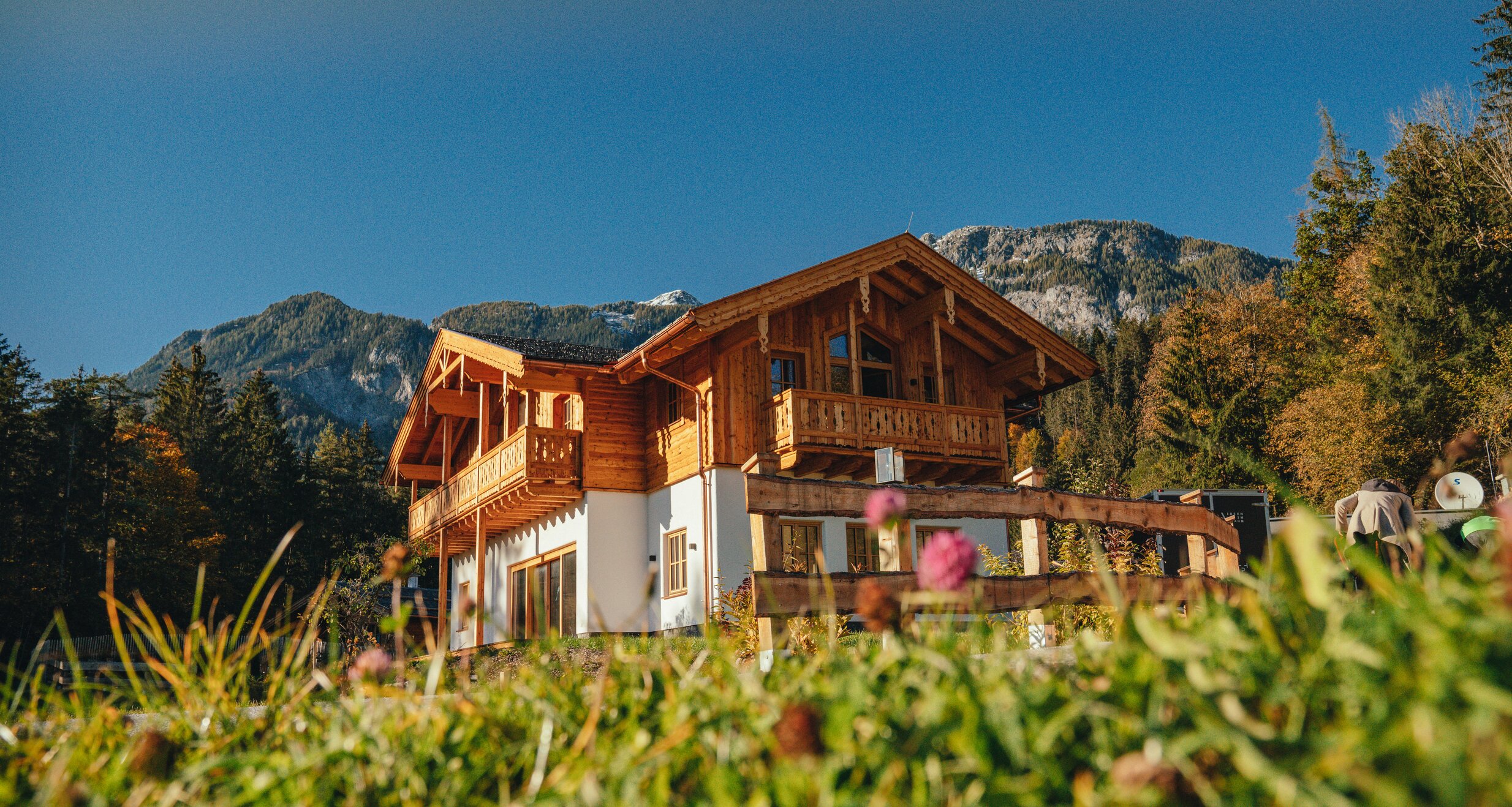 Alpen-Holzhaus mit Balkon vor Bergkulisse.