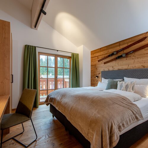 Cozy rustic bedroom with wood paneling, bed, and skis on wall