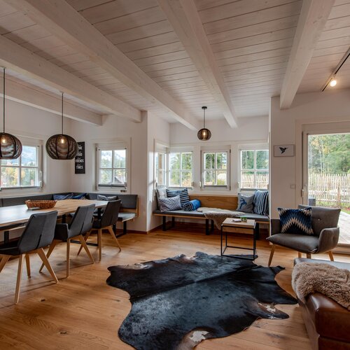 Spacious open-plan living and dining area with wooden beams and large windows